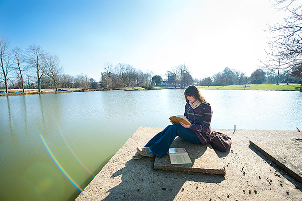 Student reading at Ecke's Pond
