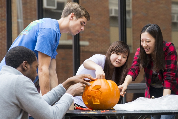 Students carve pumpkins together on the Memorial Hall patio.
