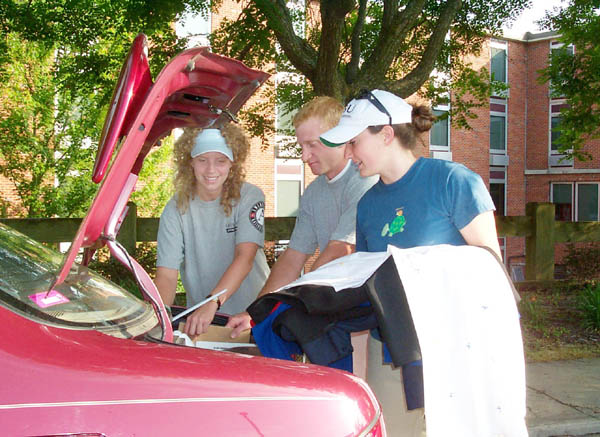 Students pack belongings into trunk of car to go home for the summer