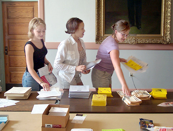 Three students compile information packets for Orientation