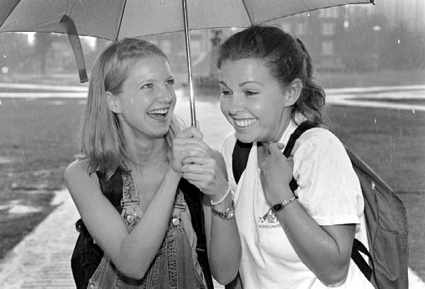 Two girls share an umbrella on a rainy day