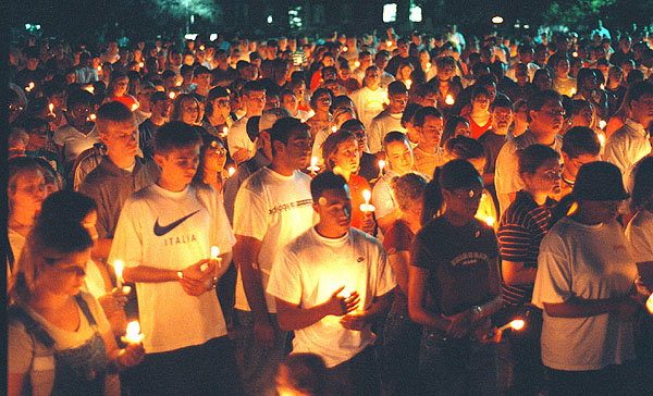 Students are bathed in red light during candlelight vigil