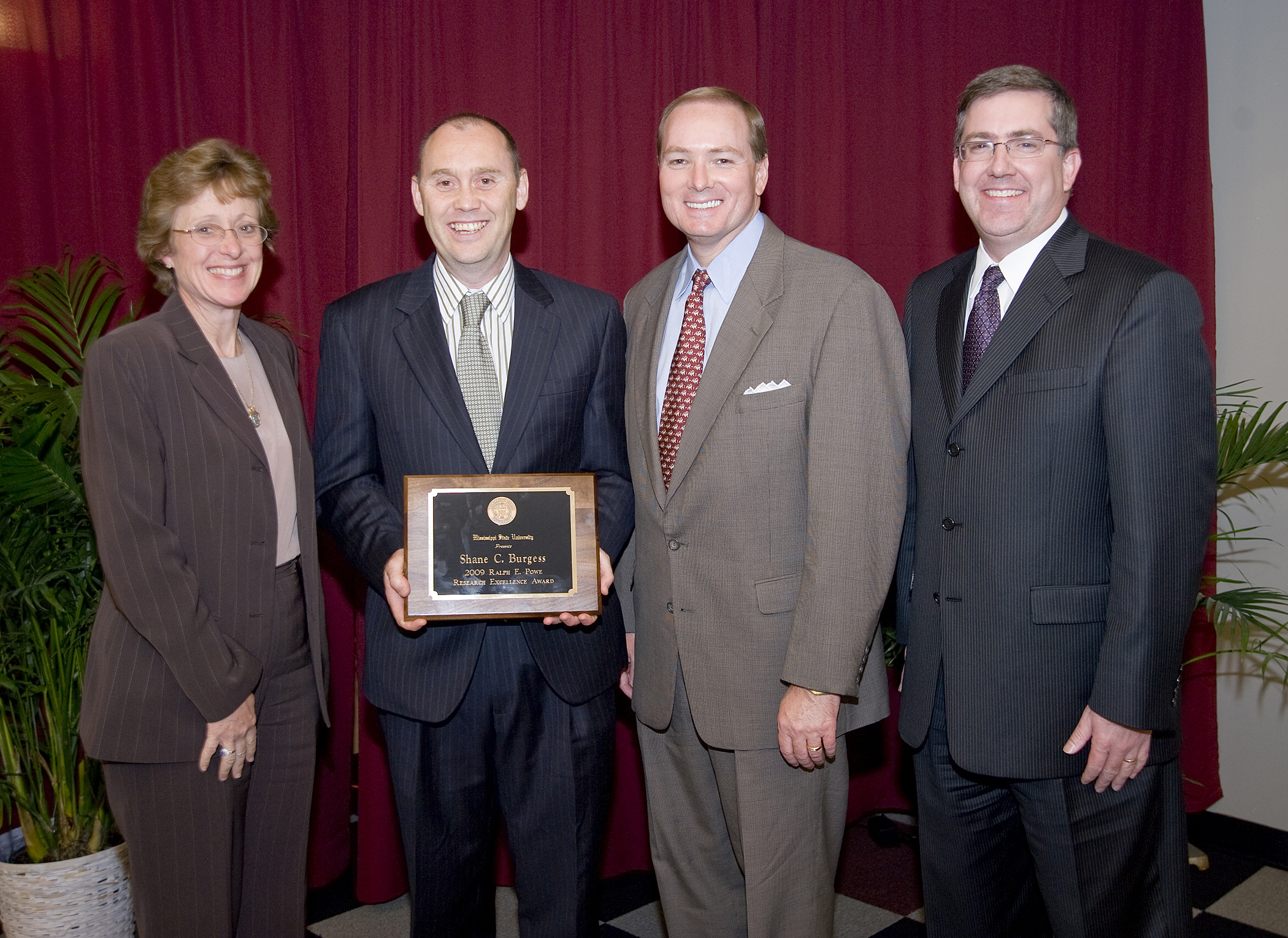 Mississippi State's 2009 Powe Award winner, Dr. Shane Burgess, second from left, is congratulated by Melissa Mixon, interim vice president of agriculture, forestry and veterinary medicine; President Mark Keenum; and Kirk Schulz, vice president of research and economic development.