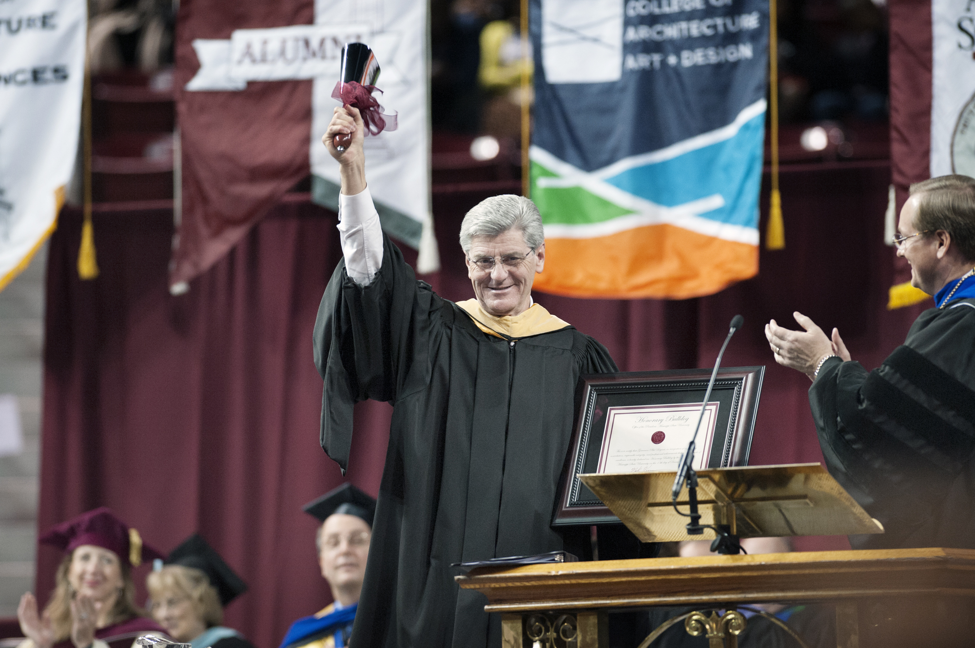 Gov. Phil Bryant rings a cowbell during Mississippi State University fall commencement ceremonies after MSU President Mark E. Keenum, right, presented him with the bell and a certificate declaring the governor an "Honorary Bulldog." The university conferred degrees upon nearly 1,400 graduates. Gov. Phil Bryant rings a cowbell during Mississippi State University fall commencement ceremonies after MSU President Mark E. Keenum, right, presented him with the bell and a certificate declaring the governor an "Honorary Bulldog." The university conferred degrees upon nearly 1,400 graduates.