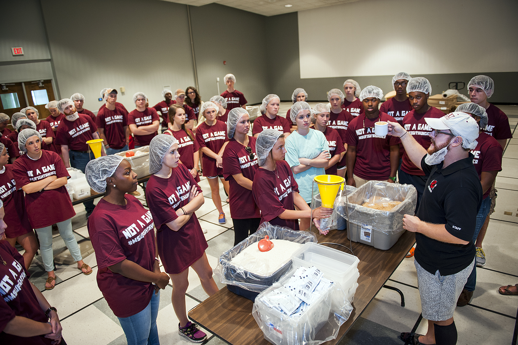 Matt Casteel, right, of the international hunger relief organization Stop Hunger Now, directs True Maroon freshmen as they prepare to package 10,000 meals to aid in the world-wide fight against hunger.