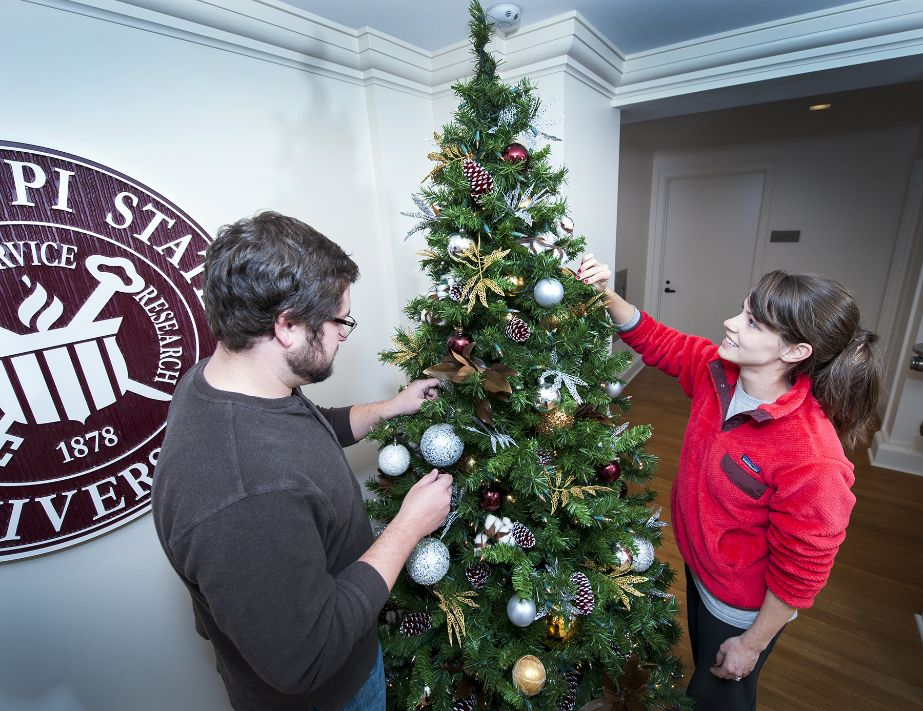 University Florist employees John B. Cetto, a junior industrial technology/manufacturing and maintenance major from Olive Branch, and Callie Paxton West, a December communication/broadcasting graduate from Tuscaloosa, Alabama, decorate a Christmas tree at the Office of the President in historic Lee Hall.
